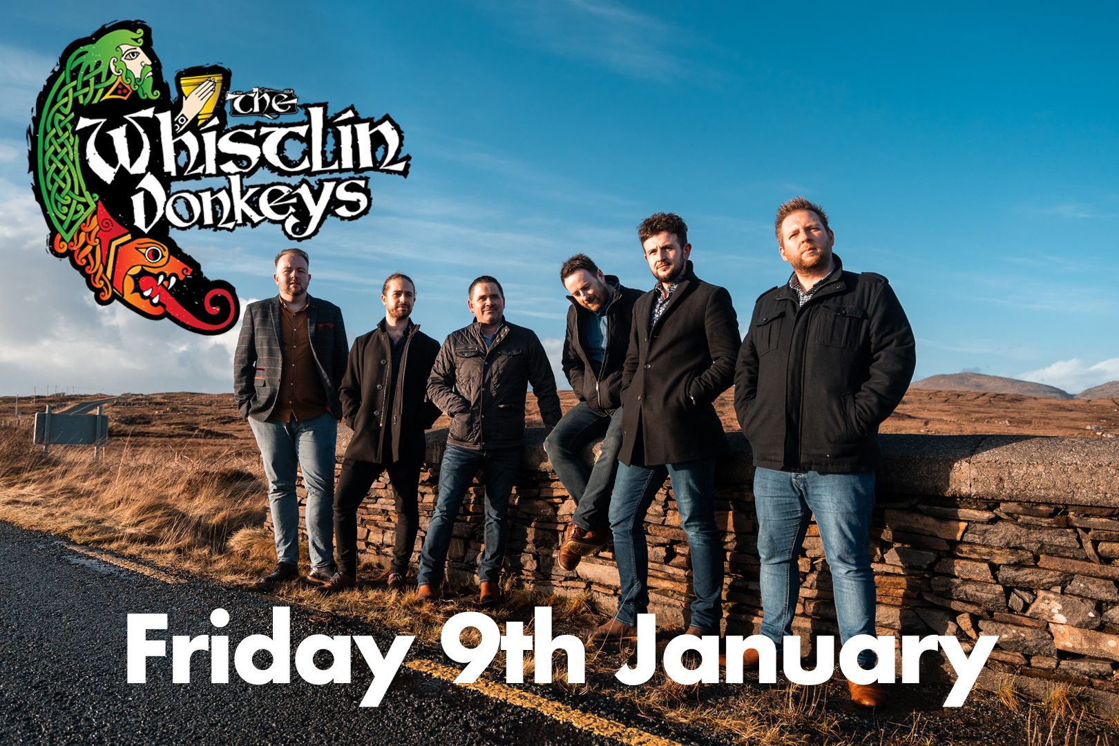 A smiling Chris Norman is wearing a black pinstriped shirt slightly open at the chest. He has shoulder-length blond-brown hair and a goatee, and is holding a guitar with a visible strap. The background features a soft gradient of blue and amber stage lighting, giving a warm and energetic concert vibe.