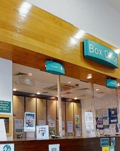 Millennium Forum Box Office with glass service windows, teal signage, and customer information displays on the counter and walls.