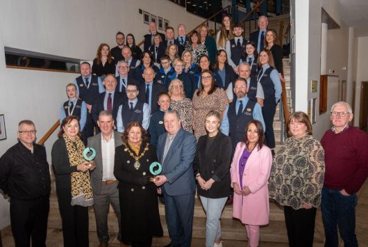 Group photo of Millennium Forum staff and board members on the venue’s main staircase, with several people in front holding awards and the Mayor of Derry present.