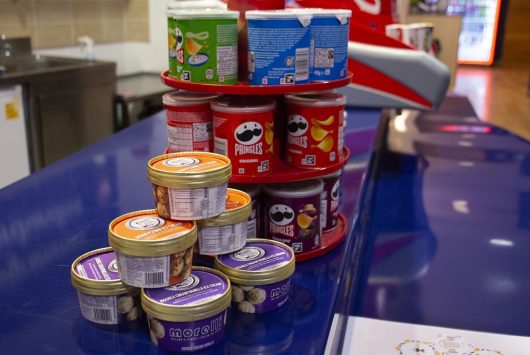 Display of snack tubs including Pringles crisps and various flavours of ice cream stacked on a counter at the Millennium Forum's refreshment area.