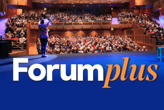 Promotional image for Forum Plus, featuring a speaker on stage addressing a full audience in the Millennium Forum auditorium. The lower half of the image shows the Forum Plus logo in white and orange text against a solid blue background.