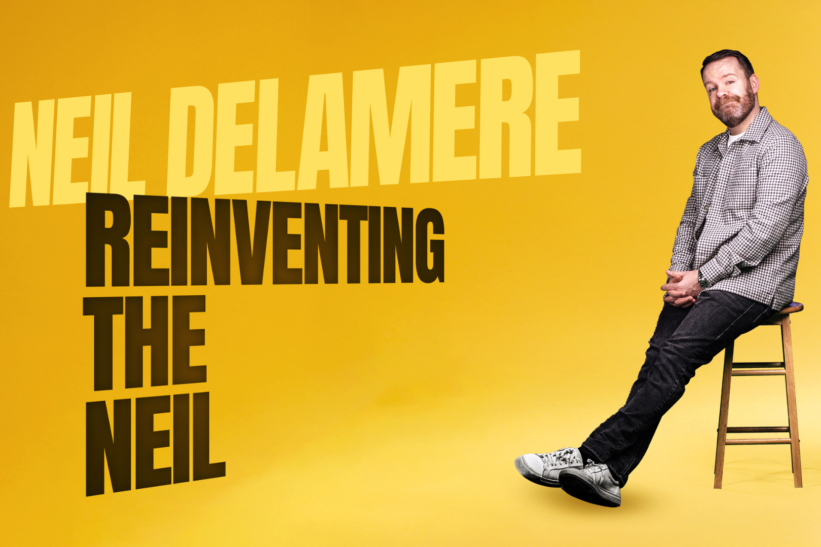 Promotional poster for Neil Delamere’s comedy show Reinventing the Neil. The background is a bold yellow gradient, with Neil Delamere seated casually on a wooden stool to the right, smiling and dressed in a grey checked shirt and black jeans. His name appears in large light yellow text, while the show title “Reinventing the Neil” is written in bold black capital letters stacked on the left. The design is clean, modern, and playful, reflecting his sharp and witty comedic style.